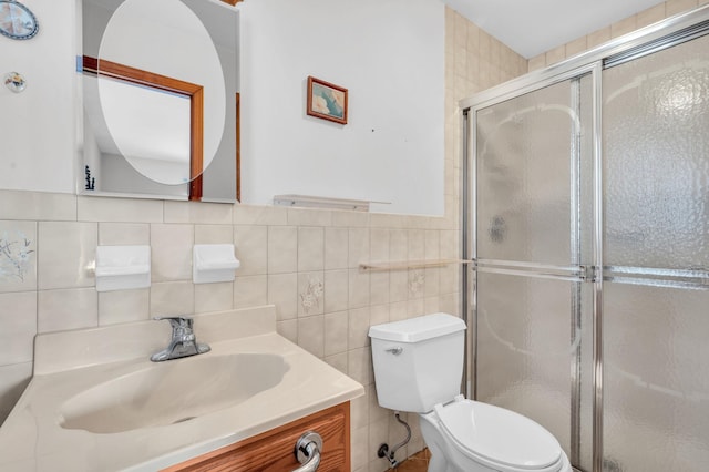 bathroom featuring vanity, a shower stall, toilet, and tile walls