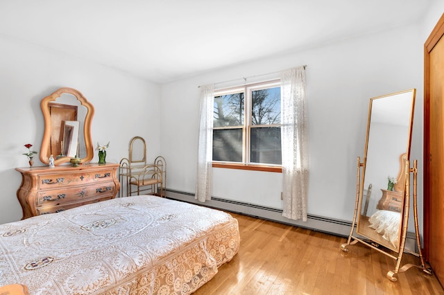 bedroom with light wood-style floors and baseboard heating