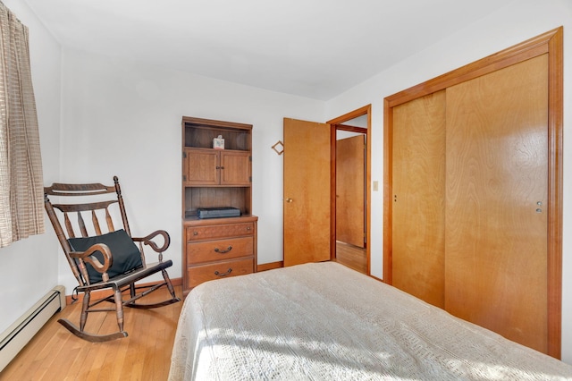 bedroom featuring a closet, light wood-type flooring, baseboards, and a baseboard radiator