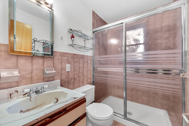 full bath with a shower stall, vanity, toilet, and tile walls