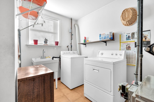 clothes washing area featuring a sink, laundry area, light tile patterned floors, and washer and clothes dryer