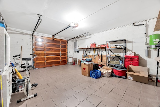 garage with concrete block wall, electric panel, and a garage door opener