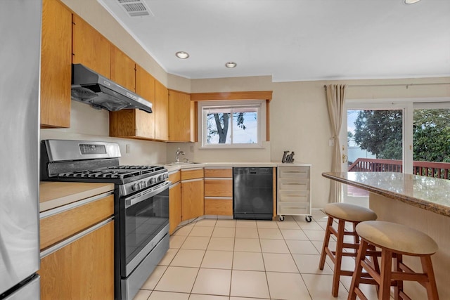 kitchen with light tile patterned flooring, under cabinet range hood, stainless steel appliances, visible vents, and light countertops