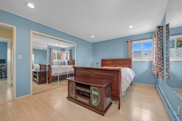 bedroom featuring recessed lighting, a closet, light wood-style flooring, baseboard heating, and baseboards