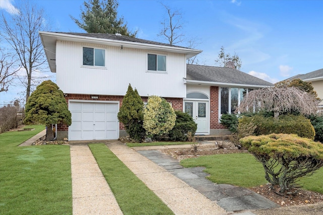 split level home featuring brick siding, a chimney, a front yard, a garage, and driveway