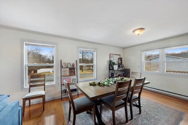 dining space featuring baseboard heating, ornamental molding, and hardwood / wood-style flooring