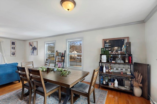 dining room with wood-type flooring and crown molding