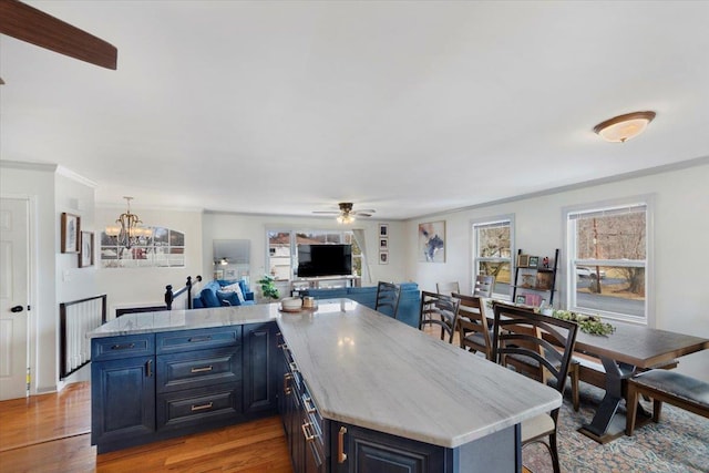 kitchen with blue cabinetry, wood-type flooring, ornamental molding, and a kitchen island