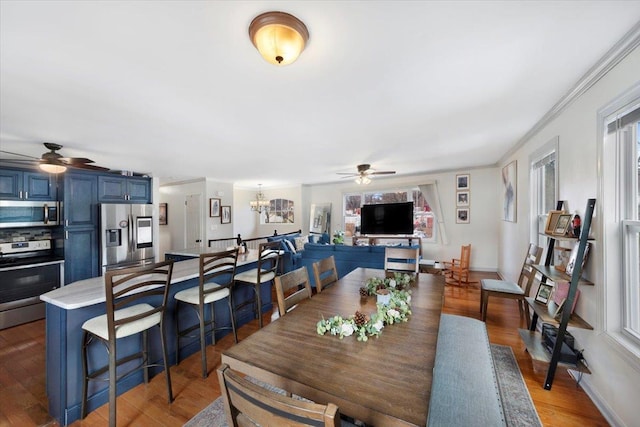 dining room featuring crown molding, dark hardwood / wood-style flooring, a healthy amount of sunlight, and ceiling fan with notable chandelier