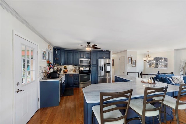 kitchen featuring decorative backsplash, blue cabinetry, stainless steel appliances, ornamental molding, and dark hardwood / wood-style flooring