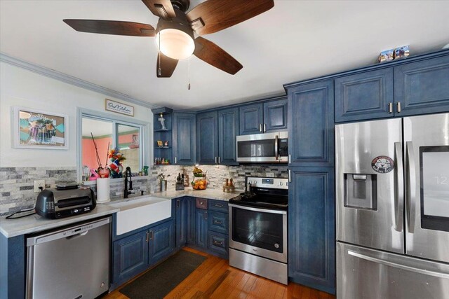 kitchen with stainless steel appliances, blue cabinets, tasteful backsplash, and sink