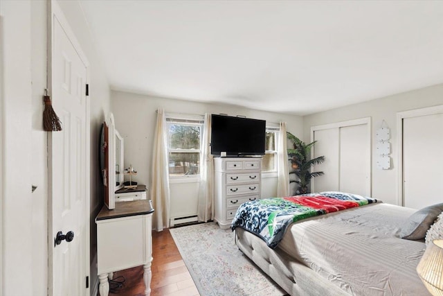 bedroom with a baseboard heating unit and hardwood / wood-style floors