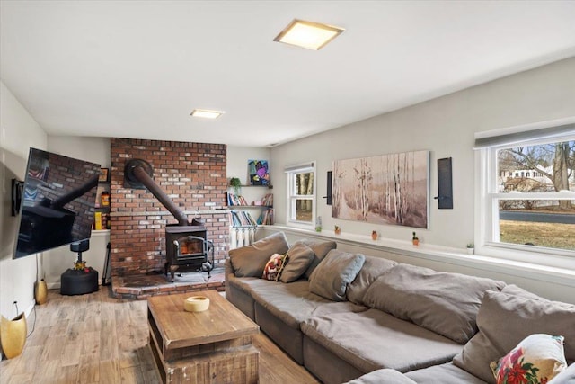 living room with a healthy amount of sunlight, light wood-type flooring, and a wood stove