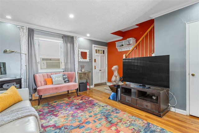 living room featuring ornamental molding, wood-type flooring, cooling unit, and a textured ceiling