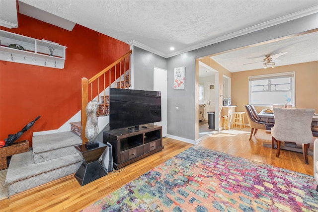 living room featuring crown molding, ceiling fan, hardwood / wood-style floors, and a textured ceiling