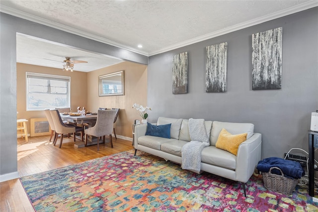 living room featuring hardwood / wood-style floors, ornamental molding, a textured ceiling, and ceiling fan