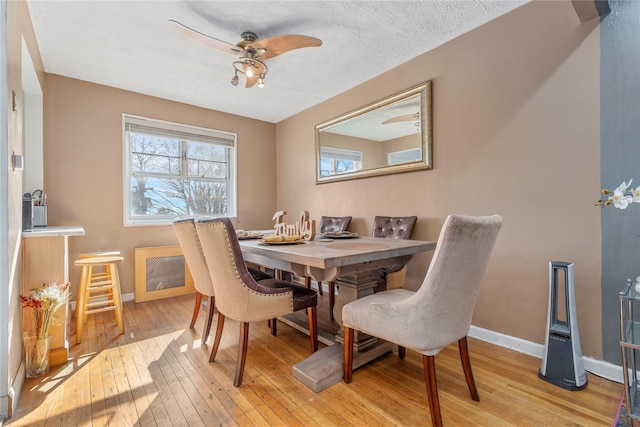 dining space with a textured ceiling, light hardwood / wood-style floors, and ceiling fan