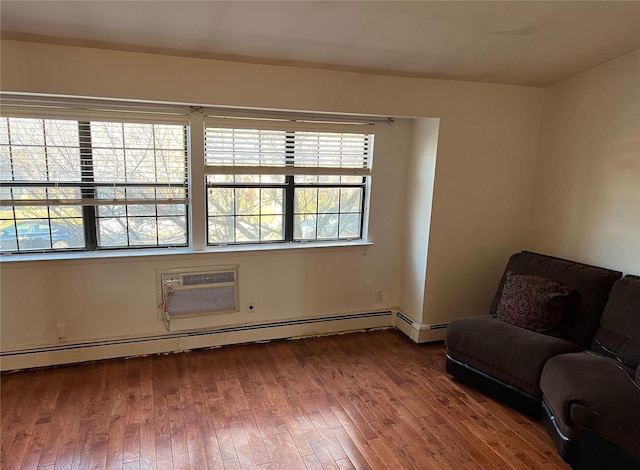 living area featuring baseboard heating, a wall unit AC, a wealth of natural light, and hardwood / wood-style floors