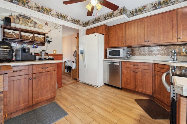 kitchen with tasteful backsplash, ceiling fan, sink, light hardwood / wood-style flooring, and appliances with stainless steel finishes