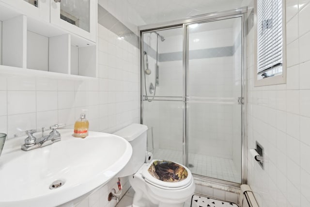 bathroom with toilet, a shower with shower door, tasteful backsplash, tile walls, and sink