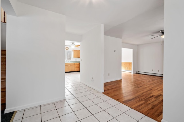 tiled empty room with ceiling fan and baseboard heating