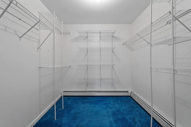 spacious closet with dark colored carpet and baseboard heating