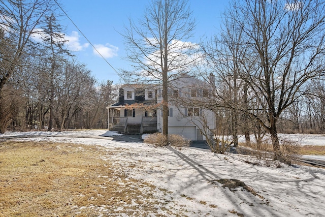 snow covered house with a garage and a porch