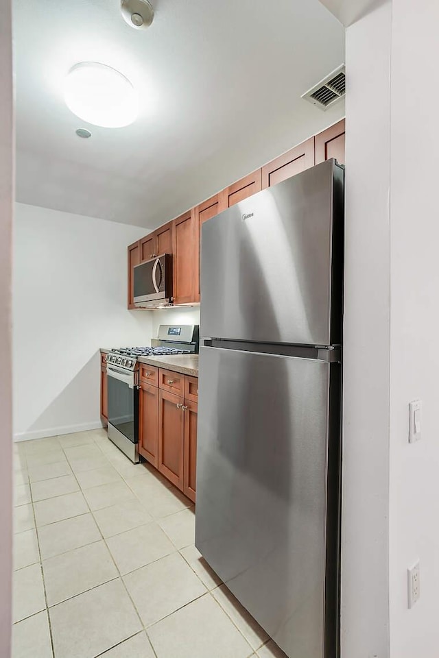 kitchen with light tile patterned floors, stainless steel appliances, visible vents, light countertops, and brown cabinets