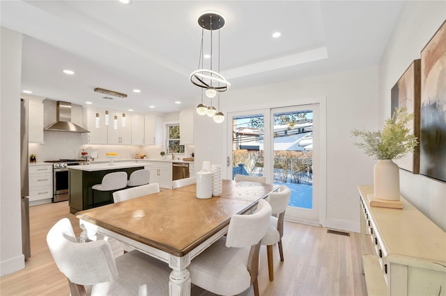 dining room with light wood-type flooring and a tray ceiling