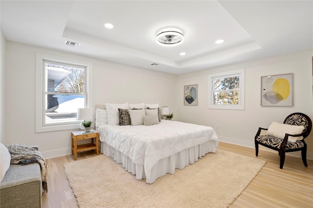 bedroom with wood-type flooring and a tray ceiling