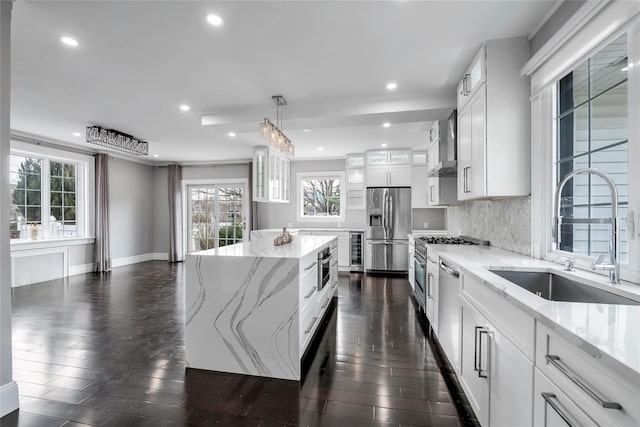 kitchen featuring a center island, stainless steel refrigerator with ice dispenser, decorative backsplash, sink, and white cabinets