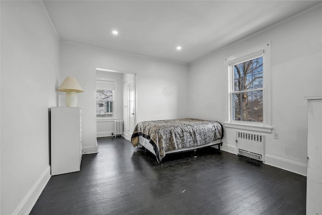 bedroom featuring multiple windows, radiator, and dark hardwood / wood-style flooring