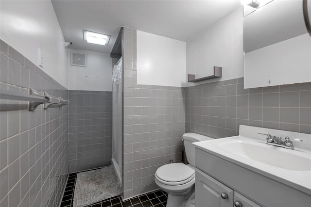 bathroom featuring toilet, vanity, tile walls, tile patterned floors, and a shower with shower curtain