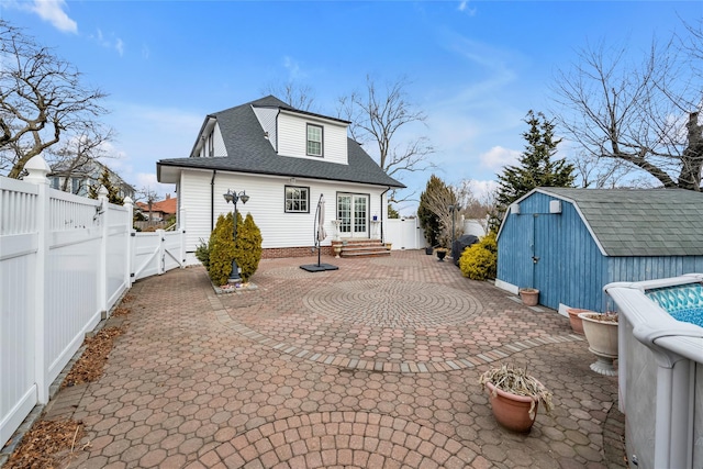 back of house with a shed and a patio