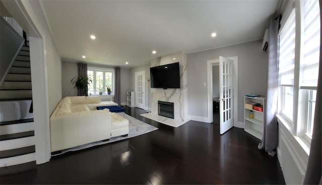 living room featuring dark wood-type flooring, a premium fireplace, and crown molding