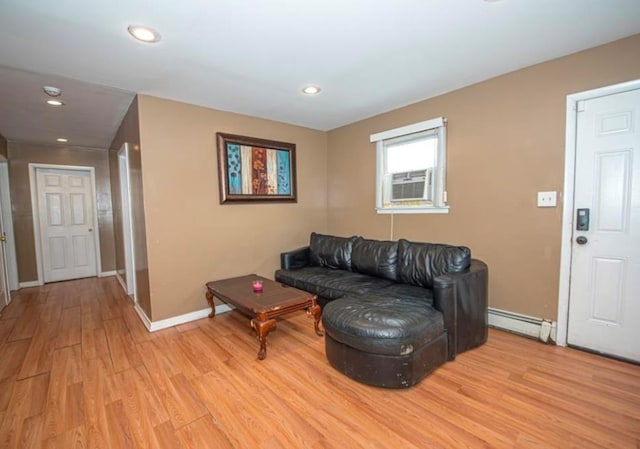 living room with a baseboard heating unit, cooling unit, and light hardwood / wood-style flooring