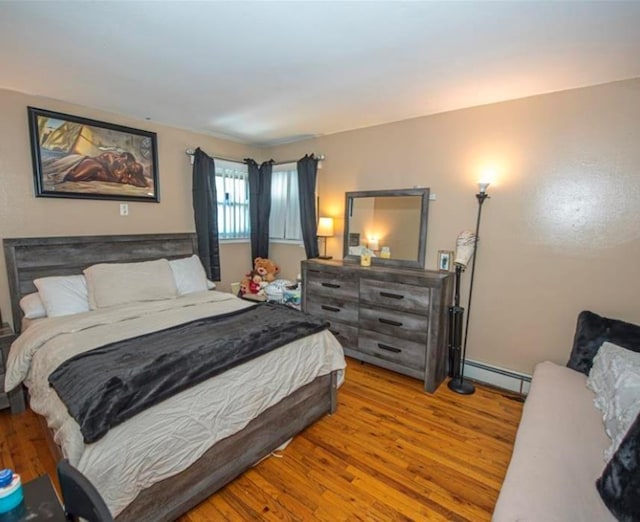 bedroom with baseboard heating and light hardwood / wood-style flooring