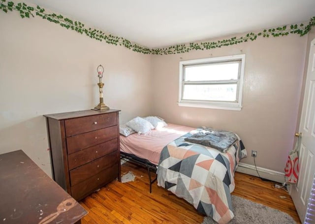 bedroom with light wood-type flooring and a baseboard heating unit