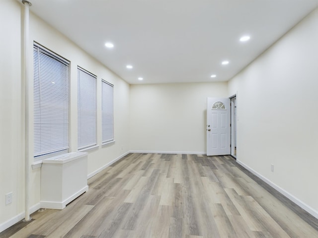 empty room with recessed lighting, light wood-style flooring, and baseboards