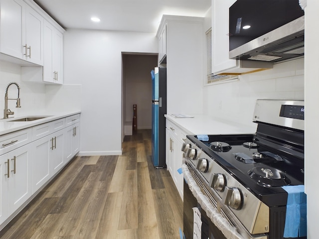 kitchen with appliances with stainless steel finishes, dark wood-type flooring, light countertops, white cabinetry, and a sink