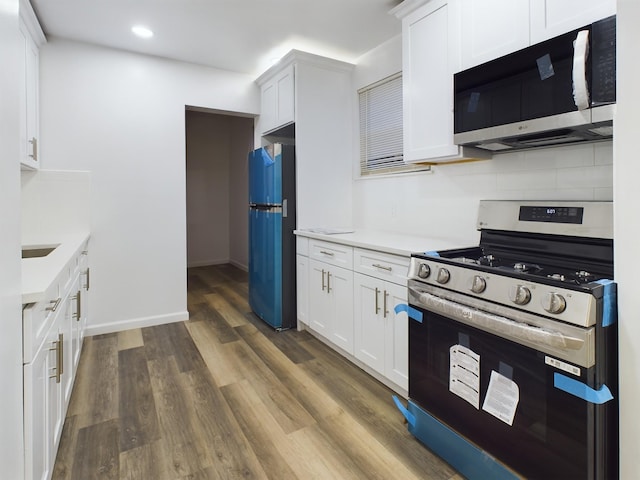 kitchen featuring white cabinets, light countertops, stainless steel range with gas cooktop, freestanding refrigerator, and dark wood finished floors