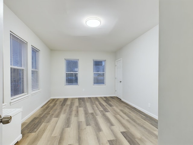 unfurnished room with light wood-type flooring and baseboards