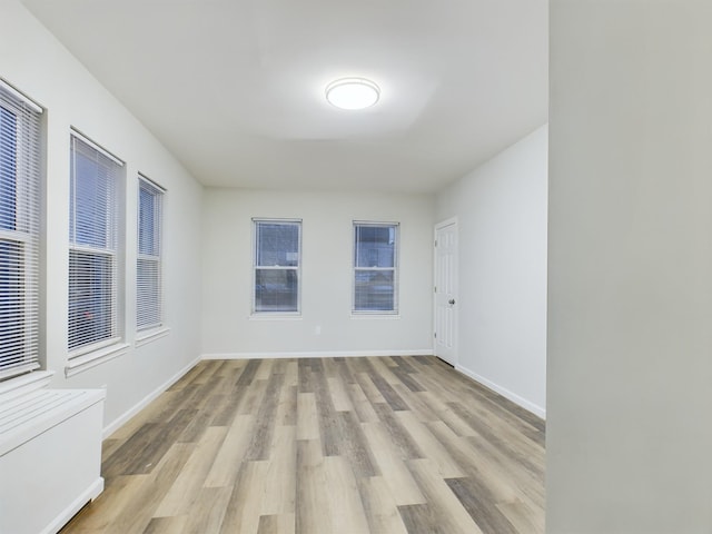 spare room featuring baseboards and light wood-style floors