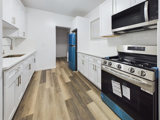 kitchen with a sink, white cabinetry, light countertops, appliances with stainless steel finishes, and light wood-type flooring