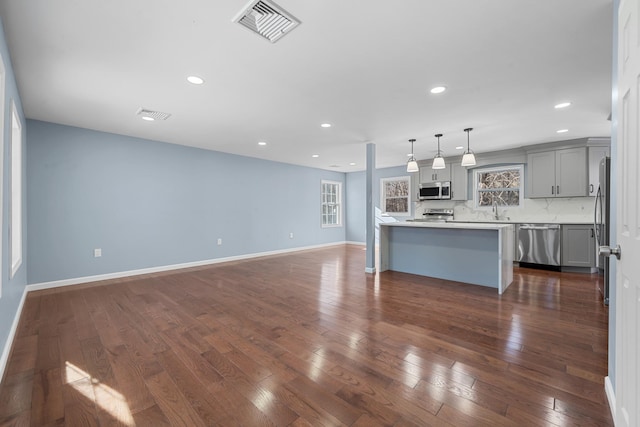 kitchen featuring appliances with stainless steel finishes, decorative light fixtures, sink, gray cabinetry, and backsplash