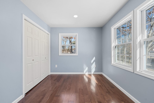 unfurnished bedroom with dark wood-type flooring and a closet