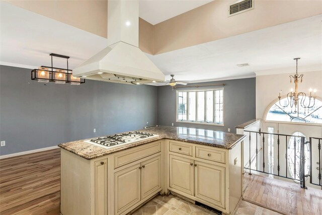 kitchen featuring island range hood, hanging light fixtures, white gas stovetop, a kitchen island, and cream cabinets