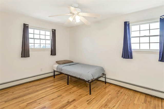 bedroom with ceiling fan, a baseboard radiator, light hardwood / wood-style floors, and multiple windows