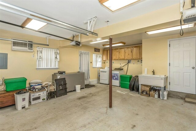 garage with a garage door opener, sink, electric panel, a wall unit AC, and washing machine and dryer