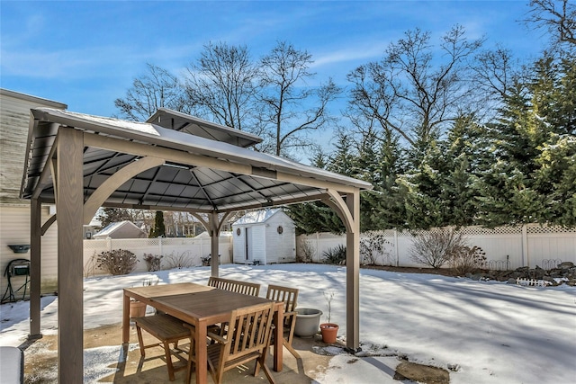 snow covered patio with a gazebo and a storage unit